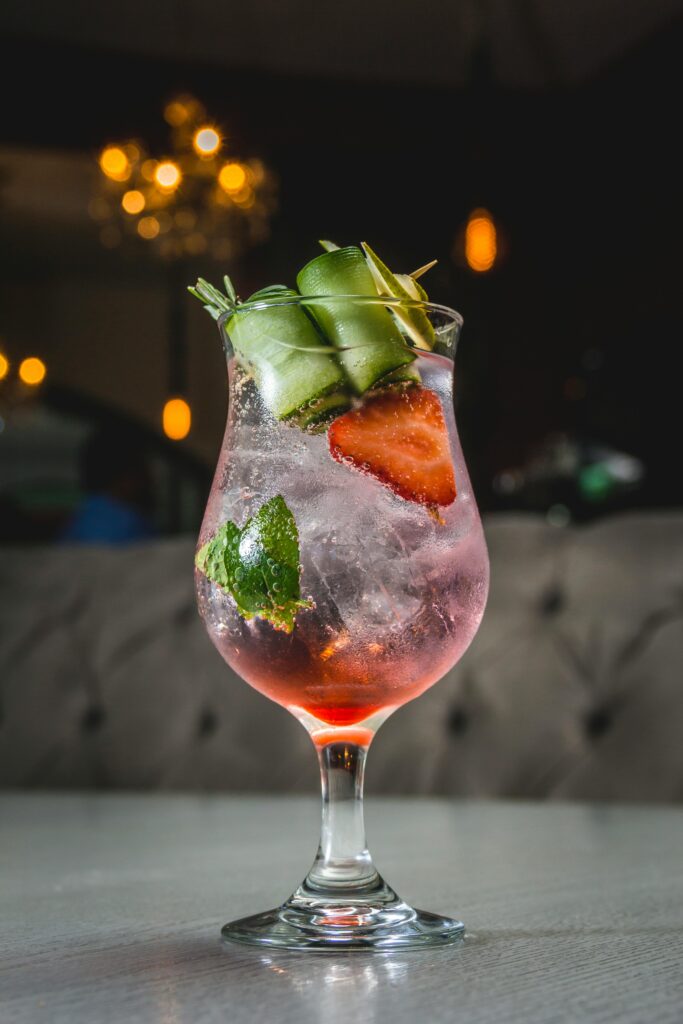Chilled pink cocktail with fruits and herbs in a stylish setting. Perfect for summer vibes.